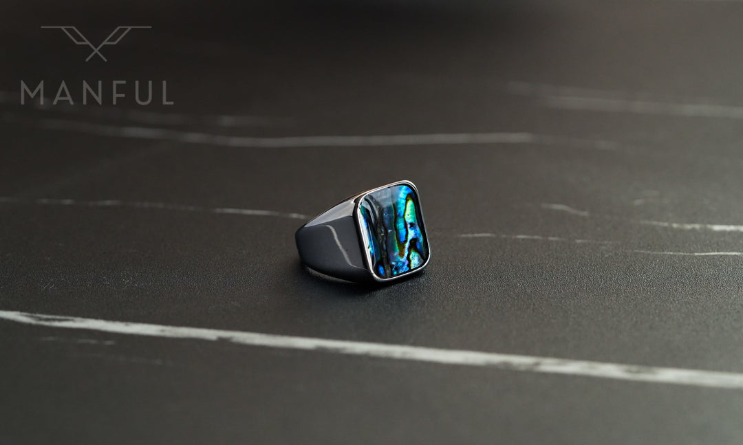 Abalone Shell Signet Ring, angled on a dark marble surface with the shell inlay catching the light