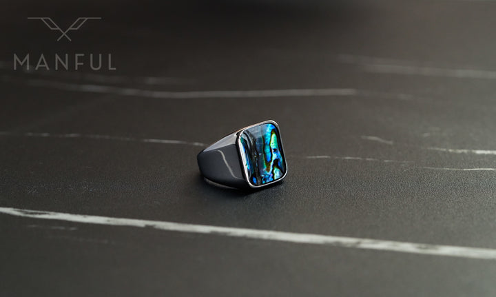 Abalone Shell Signet Ring, angled on a dark marble surface with the shell inlay catching the light