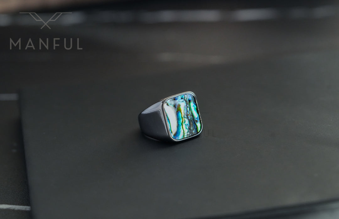 Abalone Shell Signet Ring, resting on a black card with a softly blurred dark background
