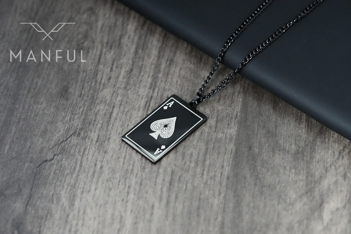 Ace Of Spades Pendant Black, resting on a wood table beside a dark leather block