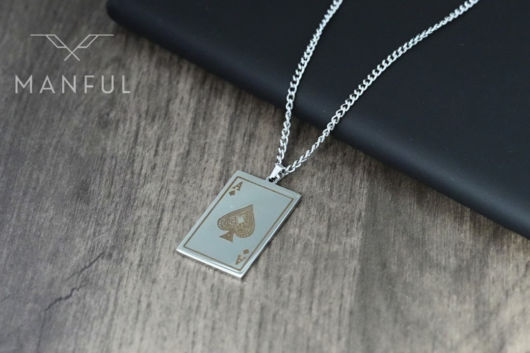 Ace Of Spades Pendant Silver, resting on a wooden surface with a dark case propped behind it