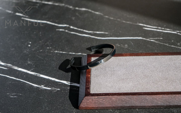 Adjustable Bangle Black, close-up on the tray's wooden corner against dark marble