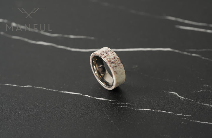Antler & Titanium Band, standing at an angle on a dark marble surface
