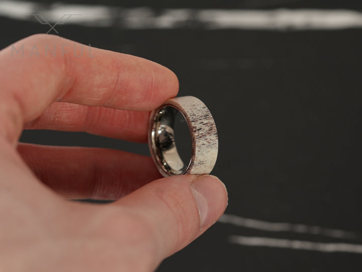 Antler & Titanium Band, held pinched between thumb and finger in close-up