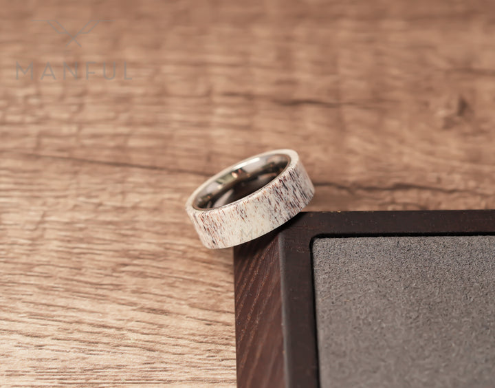Antler & Titanium Band, propped against a dark block corner in a tighter crop on woodgrain