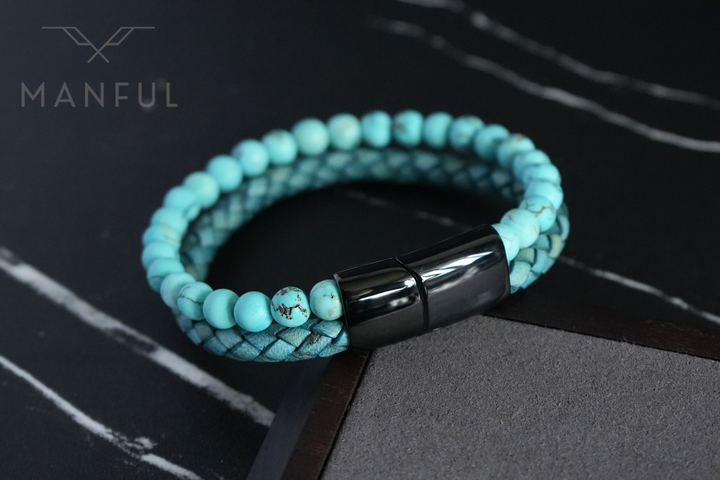 Aqua Bead And Leather Bracelet, draped over the corner of a dark wooden block on marble