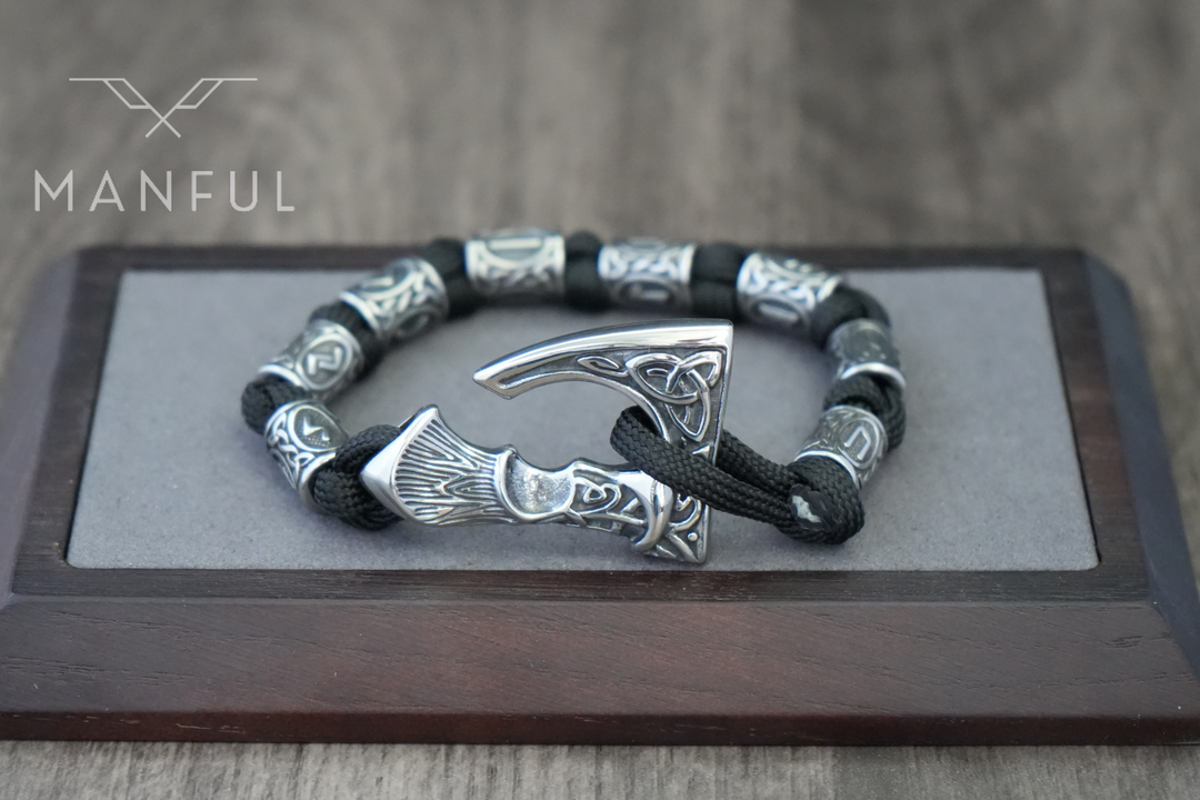 Axe Bracelet, resting on a grey display pad framed in dark wood