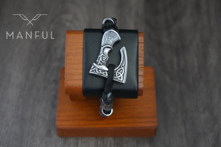 Axe Bracelet, close up on a wooden stand with the axe charm against black leather