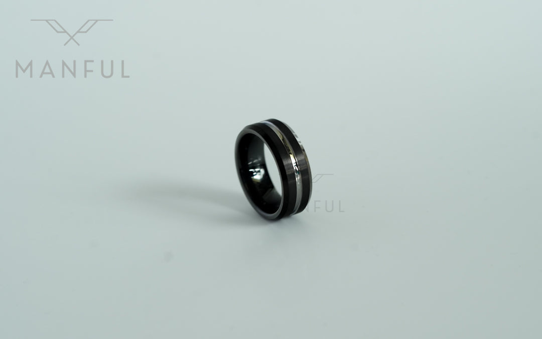Black and Silver Tungsten Ring, leaning at a steep angle on white with the band mostly in silhouette