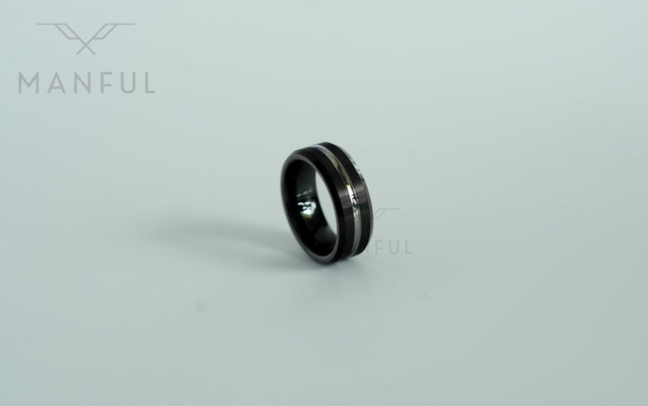 Black and Silver Tungsten Ring, leaning at a steep angle on white with the band mostly in silhouette