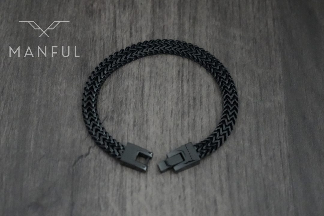 Foxtail Bracelet Black, laid in a loop on a wood surface showing the clasp