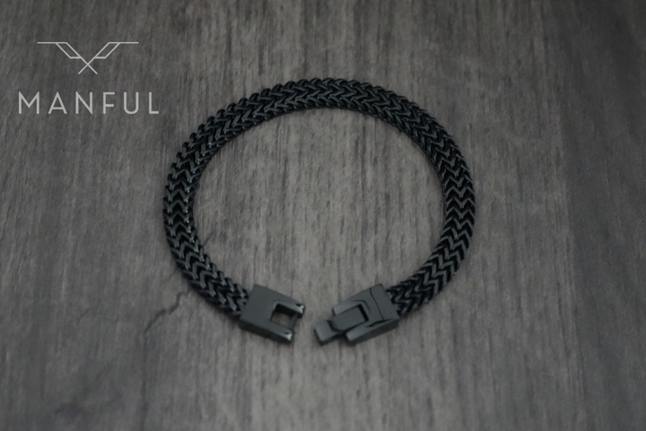 Foxtail Bracelet Black, laid in a loop on a wood surface showing the clasp
