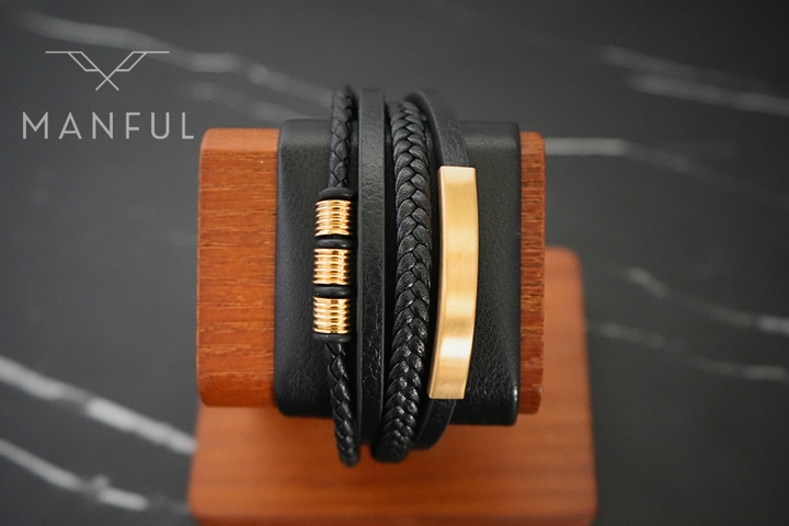 Black & Gold Leather Bracelet, draped over a wooden display stand showing the gold ID bar