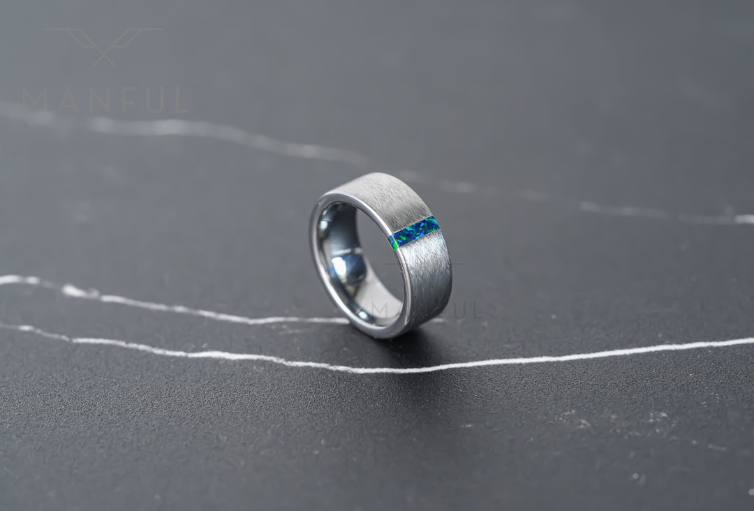 Black & Green Opal Line Tungsten Band, standing at an angle on grey marble showing the inlay