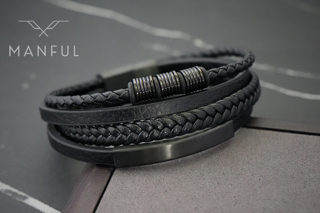 Black Leather Bracelet, angled on a dark marble surface showing the woven straps and bar