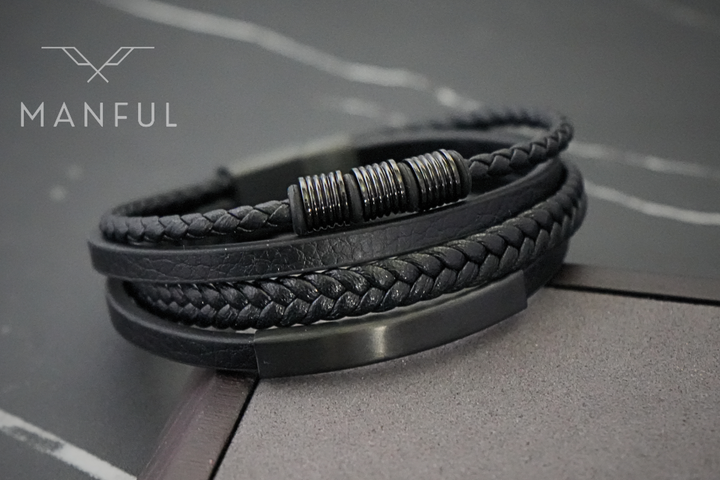 Black Leather Bracelet, angled on a dark marble surface showing the woven straps and bar