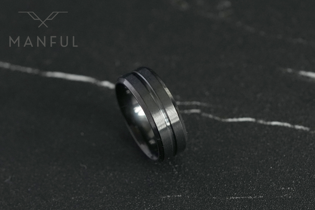 Black Onyx Band, lying flat on a dark veined marble surface with the Manful logo in the corner