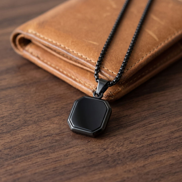 Onyx Square Necklace (Black) draped over a tan leather wallet on a walnut desk