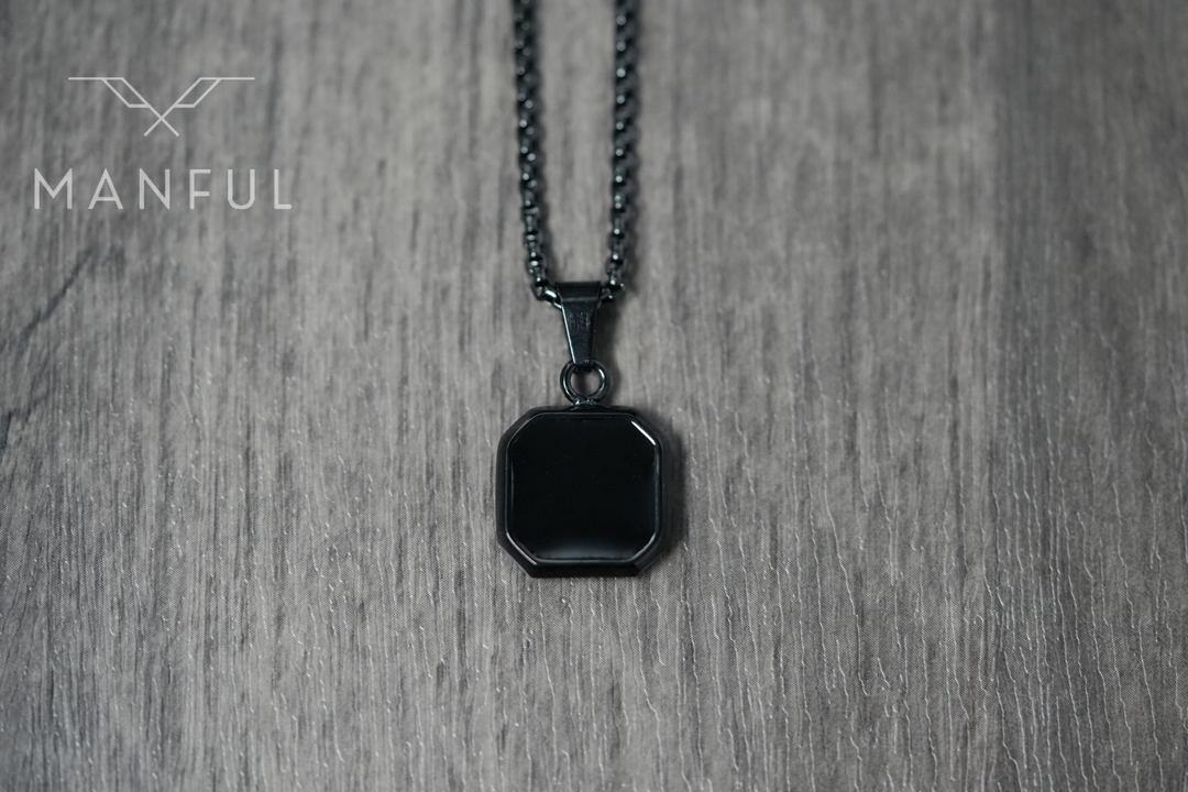 Onyx Square Necklace Black, flat lay on a wood surface, tight crop on the pendant