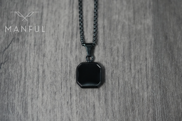 Onyx Square Necklace Black, flat lay on a wood surface, tight crop on the pendant