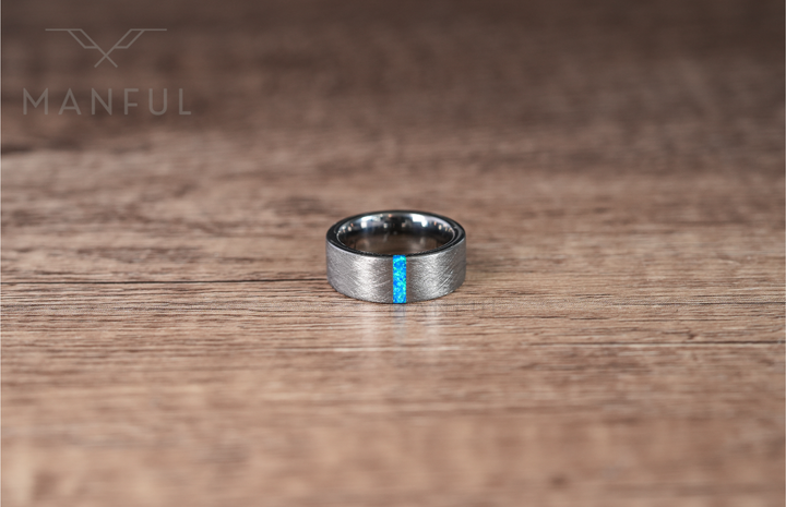 Azure Opal Line Tungsten Band, standing upright on a wooden table in a front-facing view