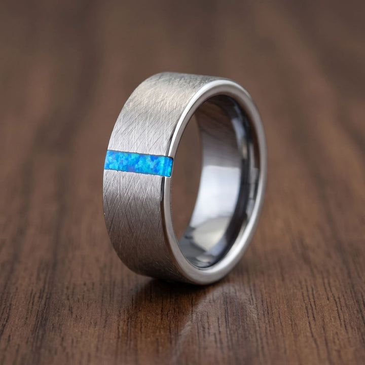 Azure Opal Line Tungsten Band standing on a walnut table