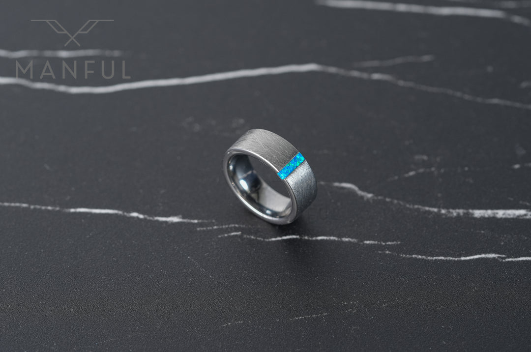 Azure Opal Line Tungsten Band, resting on a dark marble surface with plenty of empty space around it