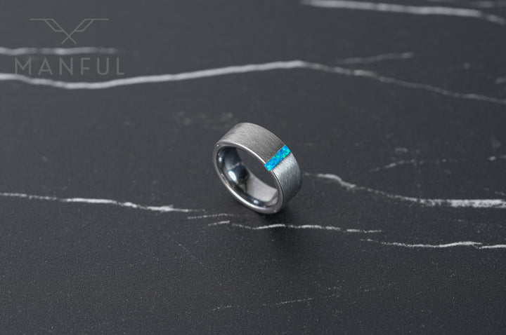 Azure Opal Line Tungsten Band, resting on a dark marble surface with plenty of empty space around it