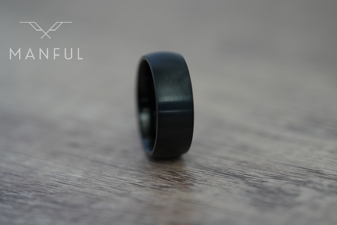 Brushed Titanium Band Black, standing on a wood-grain surface, leaning to the left