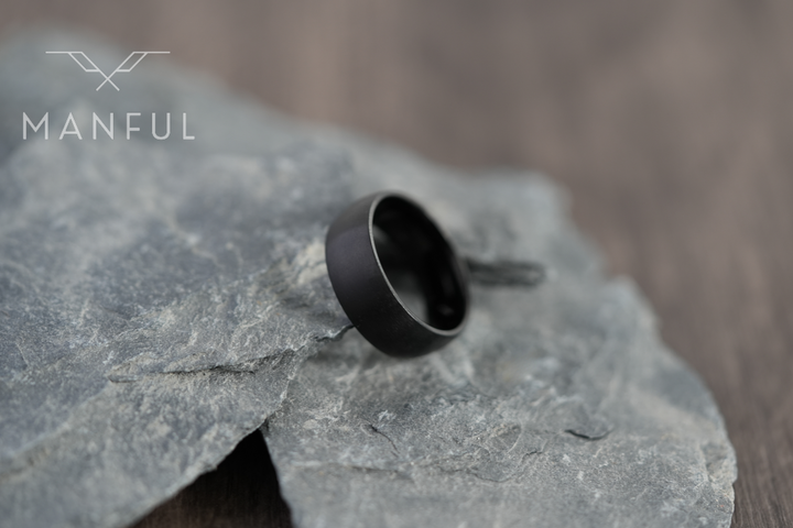 Brushed Titanium Band Black, resting on a grey stone slab against a wood-grain backdrop