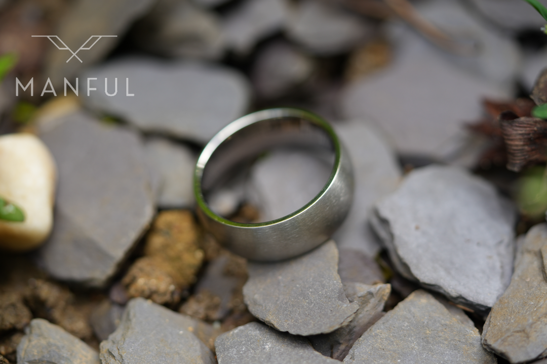 Brushed Titanium Band Silver, lying flat amid grey stone chippings outdoors