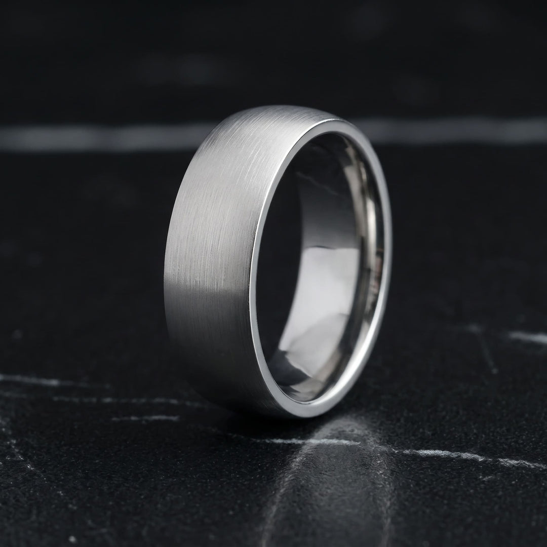 Brushed Titanium Band (Silver) standing upright on black marble with thin white veins
