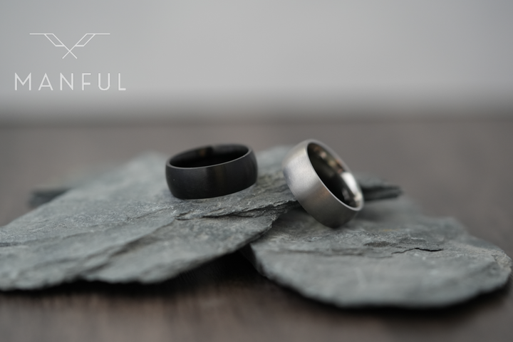 Brushed Titanium Band Silver, paired beside a black ring resting on slate stone