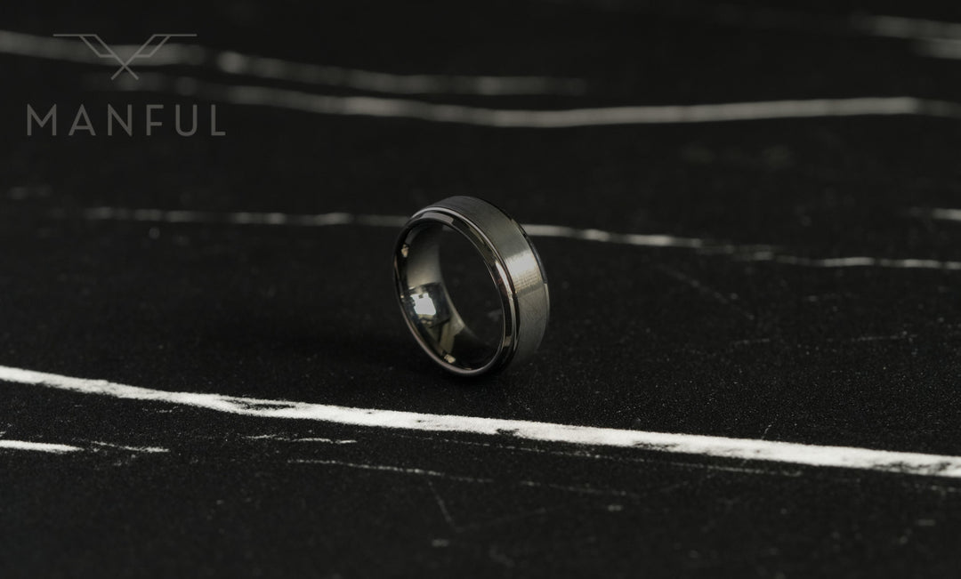 Brushed Tungsten Band Gunmetal, standing small on dark slate with light marbled veining