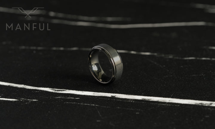 Brushed Tungsten Band Gunmetal, standing small on dark slate with light marbled veining