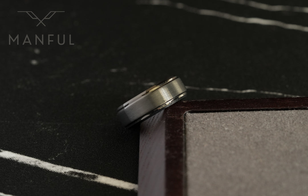 Brushed Tungsten Band Gunmetal, leaning against a wooden block corner on dark slate