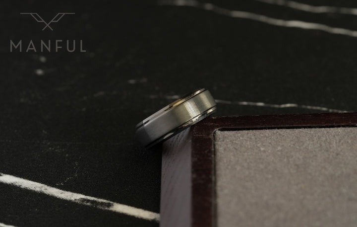 Brushed Tungsten Band Gunmetal, leaning against a wooden block corner on dark slate