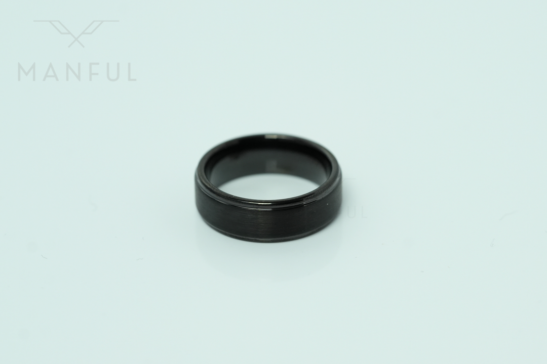 Brushed Tungsten Band Black, standing upright on a plain pale mint-green background