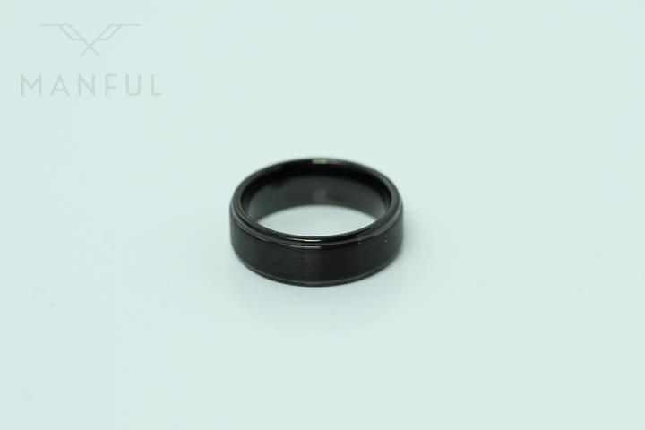 Brushed Tungsten Band Black, standing upright on a plain pale mint-green background