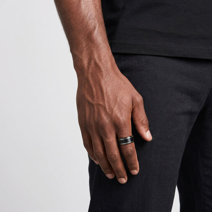 Brushed Tungsten Black & Silver Band on a man's finger, his hand hanging at his side