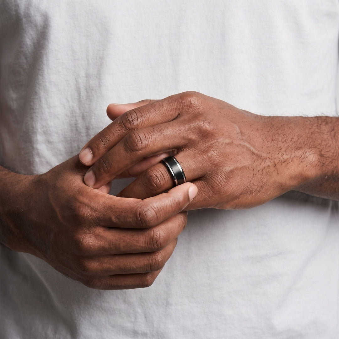 Brushed Tungsten Black & Silver Band on a man's finger as his other hand rests over it