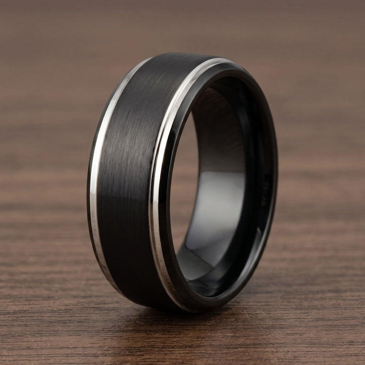 Brushed Tungsten Black & Silver Band standing on a walnut table