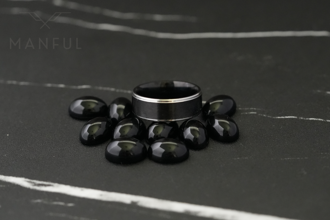 Brushed Tungsten Black & Silver Band, standing surrounded by black polished stones on dark marble