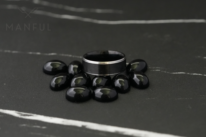 Brushed Tungsten Black & Silver Band, standing surrounded by black polished stones on dark marble