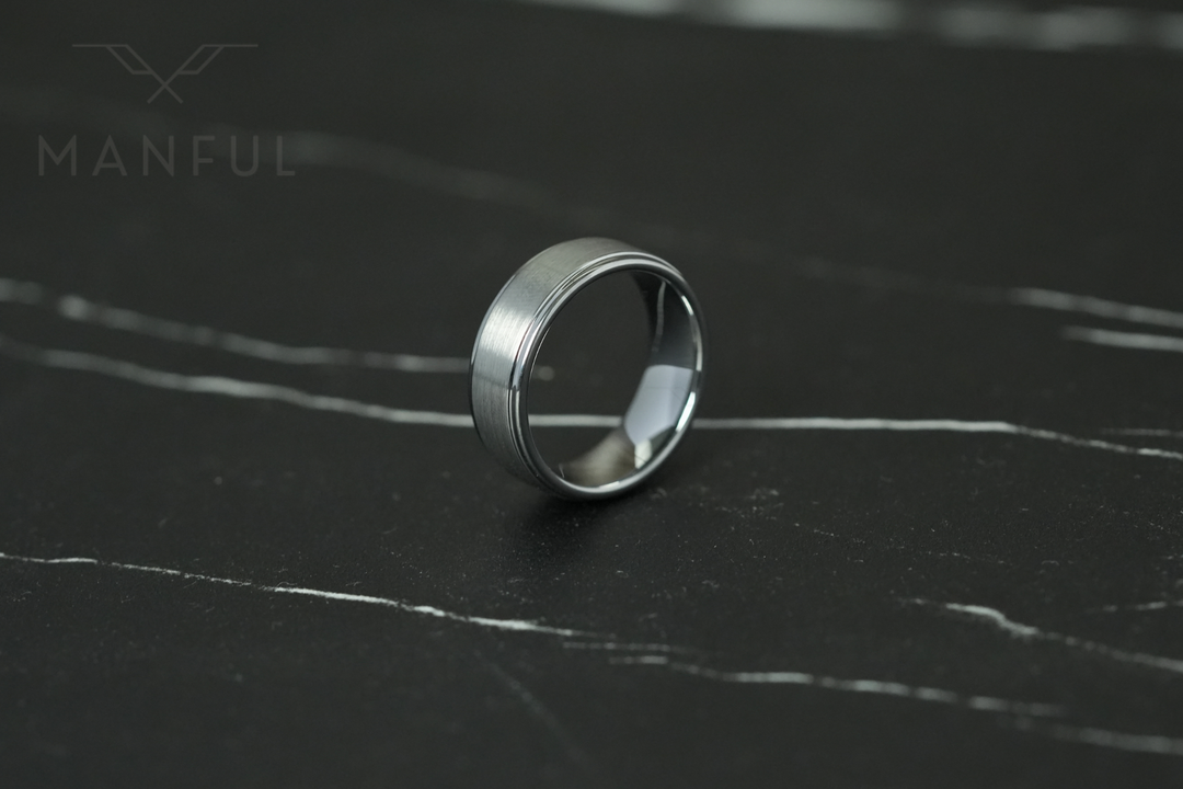 Brushed Tungsten Band Silver, lying on dark marble, leaning left