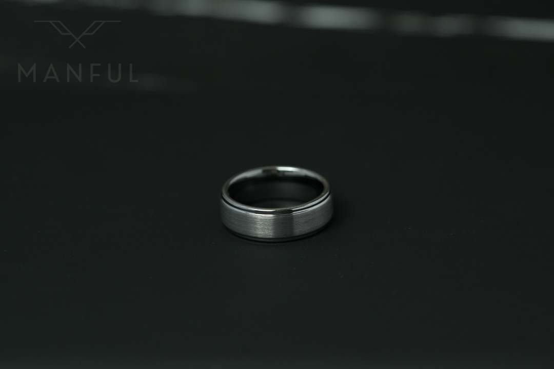 Brushed Tungsten Band Silver, standing small in frame on a black surface