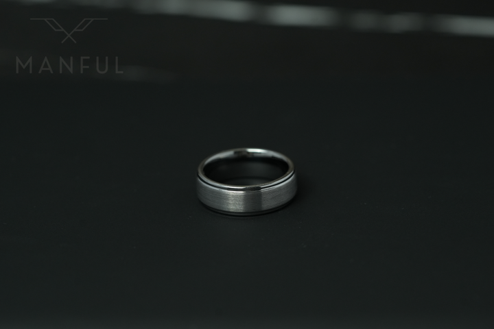 Brushed Tungsten Band Silver, standing small in frame on a black surface