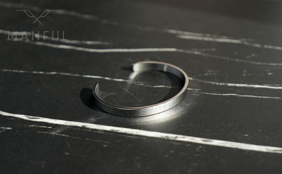 Adjustable Bangle Silver, lying open directly on a dark marble surface with pale veining