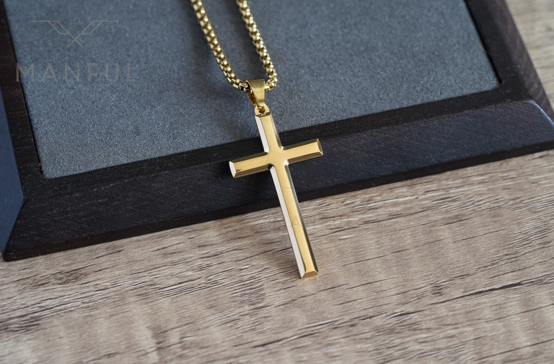 Cross Pendant Necklace Gold, laid on a wood surface with a dark leather corner behind it