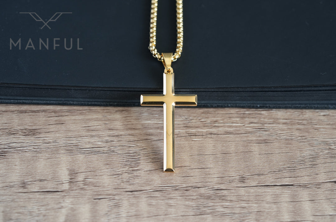 Cross Pendant Necklace Gold, laid on a wood surface against a black book edge